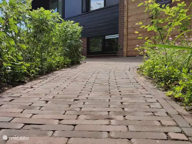 Dit is de ingang richting het huisje. Je zult verrast worden door de verrassende indeling van de tuin met verschillende zitjes.